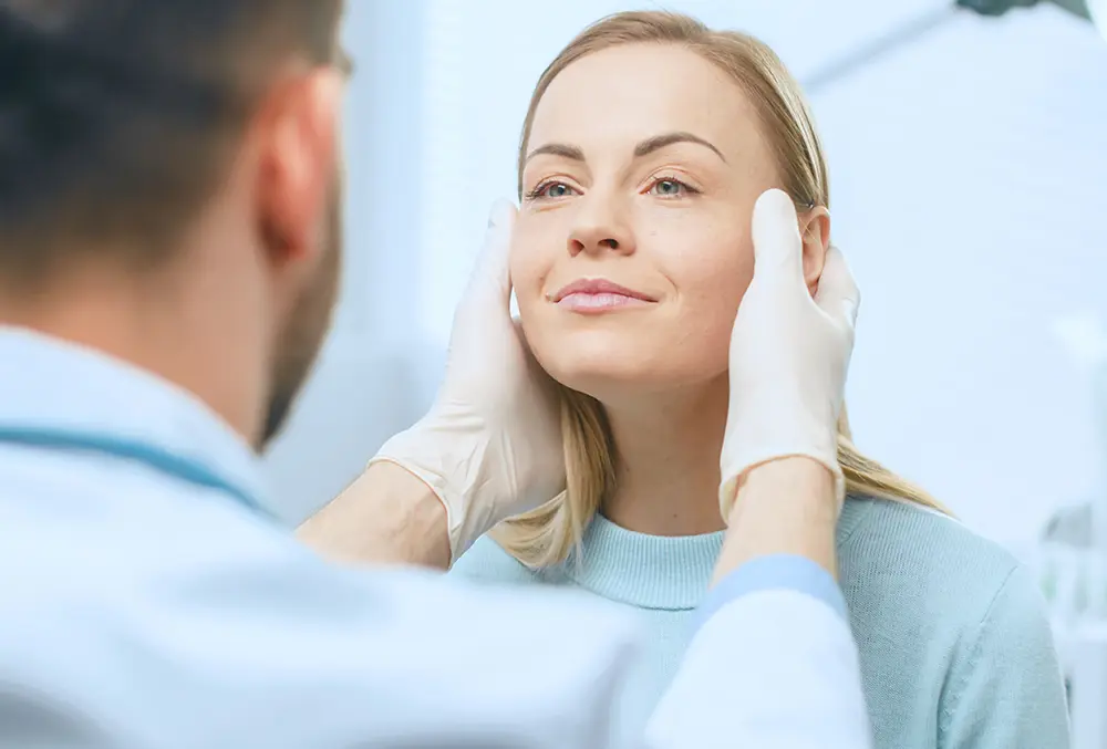 cosmetic surgeon examines beautiful womans face